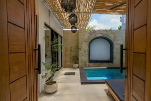 an indoor swimming pool in a house with a stone wall at Virgo Sun House in Uluwatu