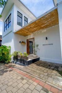 a white house with a wooden roof at Virgo Sun House in Uluwatu