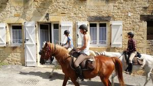 a group of people riding horses in front of a building at Au Pied du CHÂTEAU - 5 à 11 personnes - Baignade-canoë-piste cyclable à 100 m in Castelnaud La Chapelle