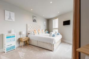 a white bedroom with a bed and a television at Harbours Edge - Front-Line Harbour Views in Poole