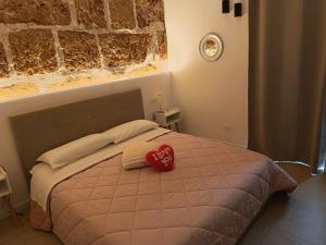 ein Schlafzimmer mit einem Bett, auf dem ein Herzkissen liegt in der Unterkunft Holiday Home MATT ROS in Noto