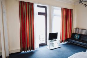 a living room with a couch and a television at Hotel Villa Kisseleff in Bad Homburg vor der Höhe