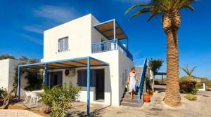 a woman walking up the stairs of a white house with a palm tree at Palatia Village Hotel Apartments in Hersonissos
