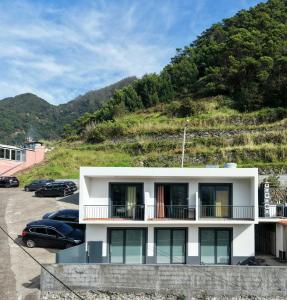 a white building with cars parked in a parking lot at Seaside & Levada Escape in Machico