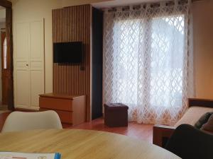 a living room with a table and a large window at Chambres d'Hôtes Grange Carrée in Saint-Rémy
