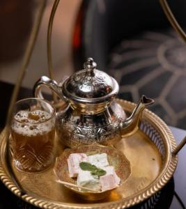Ein Teekessel und ein Glas Bier auf einem Tablett in der Unterkunft Riad Dalal in Fès