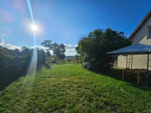 a sun shines on a grass field next to a house at Poddasze nad jeziorem Piaski in Wolin