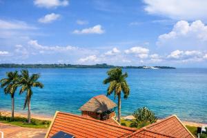a view of the ocean with palm trees and a building at Sienna Beach Hotel - Entebbe in Entebbe
