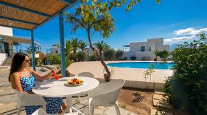 a woman sitting at a table with a bowl of fruit at Palatia Village Hotel Apartments in Hersonissos