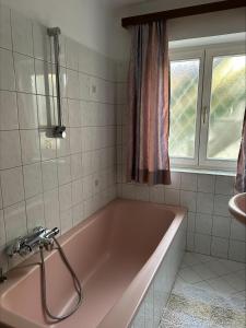 a pink bath tub in a bathroom with a window at Ferienwohnung Wasserfall in Golling an der Salzach +11 photos