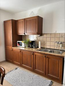 a kitchen with wooden cabinets and a sink and a microwave at Ferienwohnung Wasserfall in Golling an der Salzach