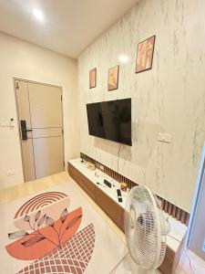 a living room with a television and a fan at The Cust Phuket in Ban Khok Chang