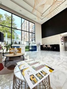 a lobby with a table and chairs and windows at The Cust Phuket in Ban Khok Chang