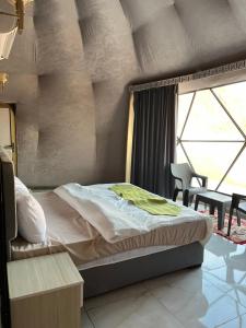 a bedroom with a bed and a table and a window at SELEN RUM LUXURY CAMP & Jeep Tours in Wadi Rum