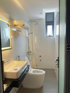 a white bathroom with a sink and a toilet at Phao Hotel in Vung Tau
