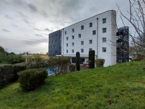 a white building sitting on top of a green hill at Hotel Arena Toulouse in Toulouse