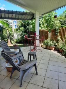 a patio with two chairs and a table and chairs at Chambre cosy avec piscine in Saint-Benoît