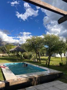 two people in a swimming pool in a yard at Selah Cabaña de dos habitaciones in Villa Las Rosas