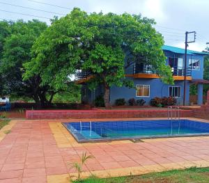 a swimming pool in front of a house with a tree at Mist Leaf Villa Mahabaleshwar in Mahabaleshwar