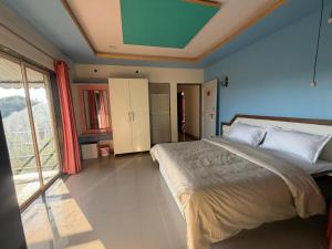 a bedroom with a large bed and a large window at Mist Leaf Villa Mahabaleshwar in Mahabaleshwar +4 photos