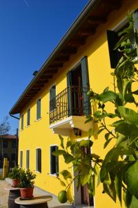 un edificio amarillo con balcón y macetas en Alloggi e Trattoria Agli Alberoni, en Brussa
