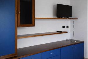 a room with a tv on a wall with blue cabinets at Terrazza sul Mare Case Vacanze in Capo Rizzuto