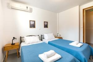 two beds in a white room with blue sheets at Blue Bay Apartment in Gouvia +29 photos