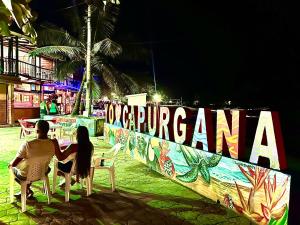a man and woman sitting at a table in chairs in front of a wall at Hotel Magic Capurganá in Capurganá