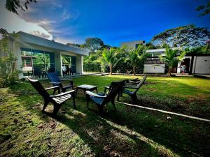three benches sitting in the grass in front of a house at Hotel Magic Capurganá in Capurganá