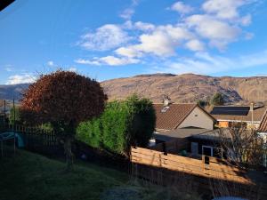 a house with a fence and mountains in the background at An Sealladh in Fort William