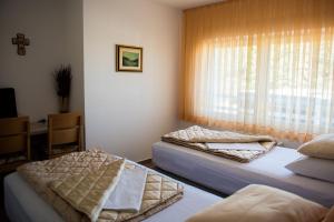 two beds in a room with a window at Hotel Pervan in Međugorje