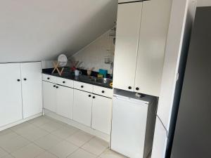 a kitchen with white cabinets and a sink at Atico con terraza al mar in Mogro +2 photos