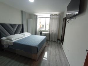 a bedroom with a bed and a window and a table at Hotel Samana'Inn in Arequipa