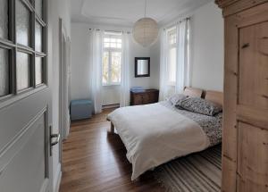 a bedroom with a bed with white sheets and windows at Jugendstil Ferienwohnung Neustadt in Neustadt an der Weinstraße