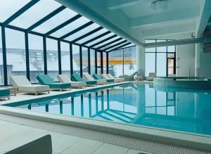 a pool in a building with chairs and a swimming pool at Large Studio - Balcony - Spa and Gym in Building - Free Parking in Sinaia