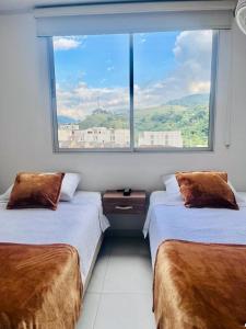 two beds in a room with a large window at Hotel Terraza in Floridablanca
