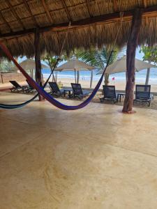 a hammock on a beach with chairs and umbrellas at Casa Nhisdao in San Agustinillo