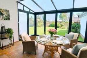 a conservatory dining room with a glass table and chairs at Haus Sonneneck 1 in Bad Zwischenahn +11 photos
