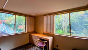 a room with a desk and two chairs and windows at 奈良春日 鹿のや in Nara