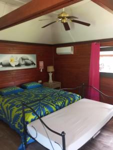 a bedroom with a bed and a ceiling fan at Raiatea Airport Bungalow in Uturoa