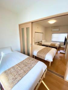 a hotel room with two beds and a mirror at AJITO Hostel 別館 in Shingū