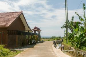 a road next to a house with a fence at Omah Ulin in Bandongan