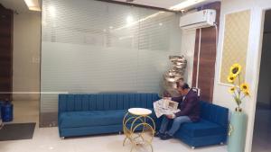 a man sitting on a blue couch reading a newspaper at Hotel Singh Empire in Sāgar
