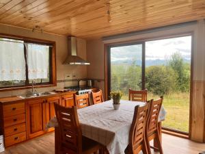 a kitchen with a table and a large window at Cabaña Caburgua vista al Volcán, Senderos del Bosque in Pucón