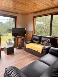 a living room with a couch and a piano at Cabaña Caburgua vista al Volcán, Senderos del Bosque in Pucón
