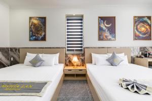 two beds in a room with white walls at Nghia Lan Maison - DL Center in Da Lat