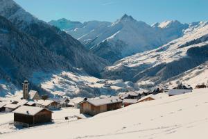 a village in the snow with mountains in the background at Family-friendly apartement in Lumbrein