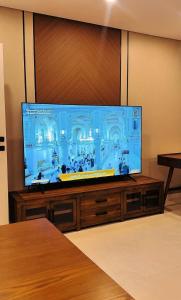 a large flat screen tv on a wooden entertainment center at AINOSAH Residences in Medina
