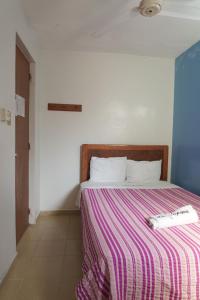 a bed with a striped blanket and a remote control on it at Hotel Reforma in Veracruz