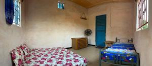 a bedroom with a bed and a blue door at Ibel dans le pays Bassaris in Kédougou